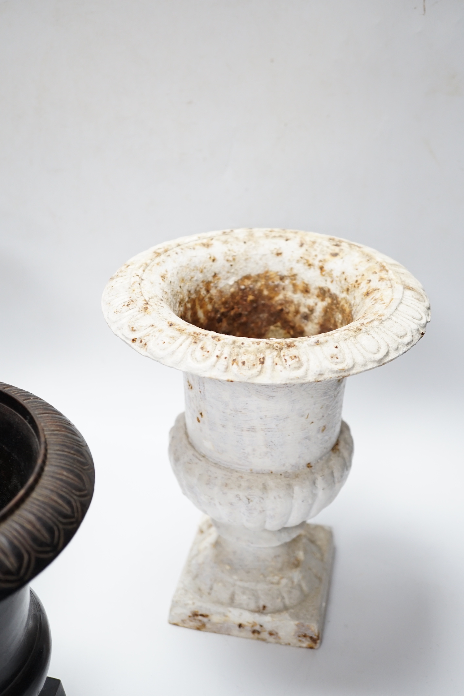 A pair of painted cast iron urns and another, tallest 23cm